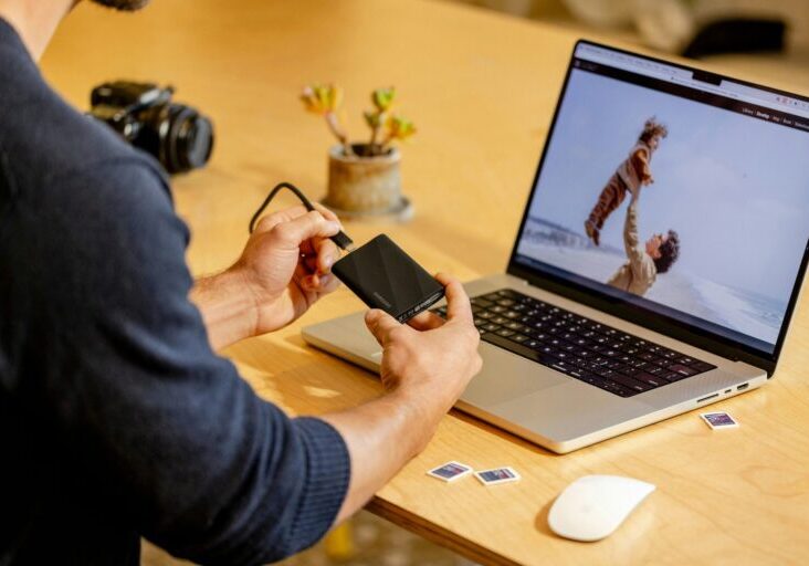A man sitting at a table with a laptop and cell phone